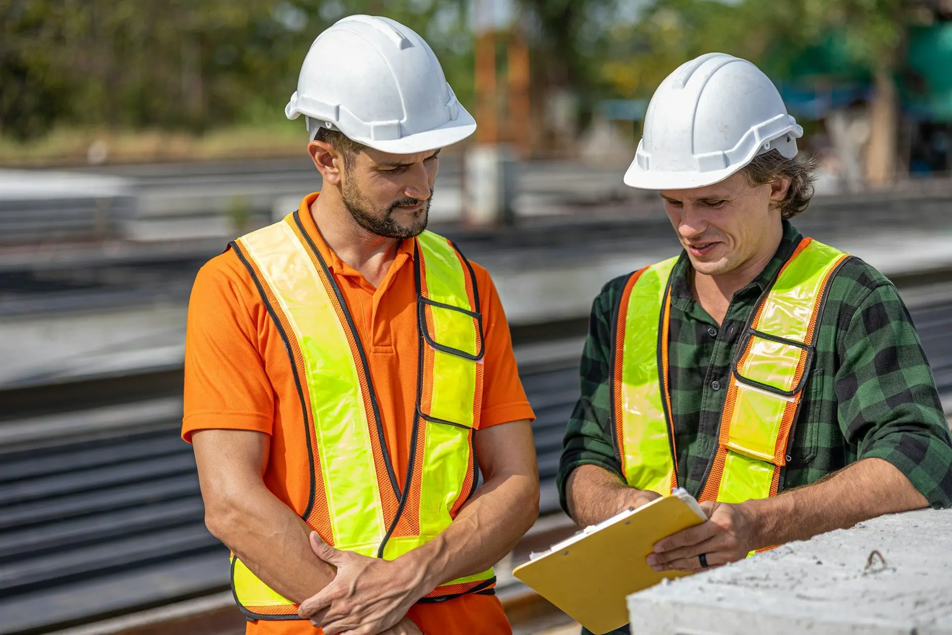 Deux techniciens en équipement de sécurité consultent des documents sur chantier