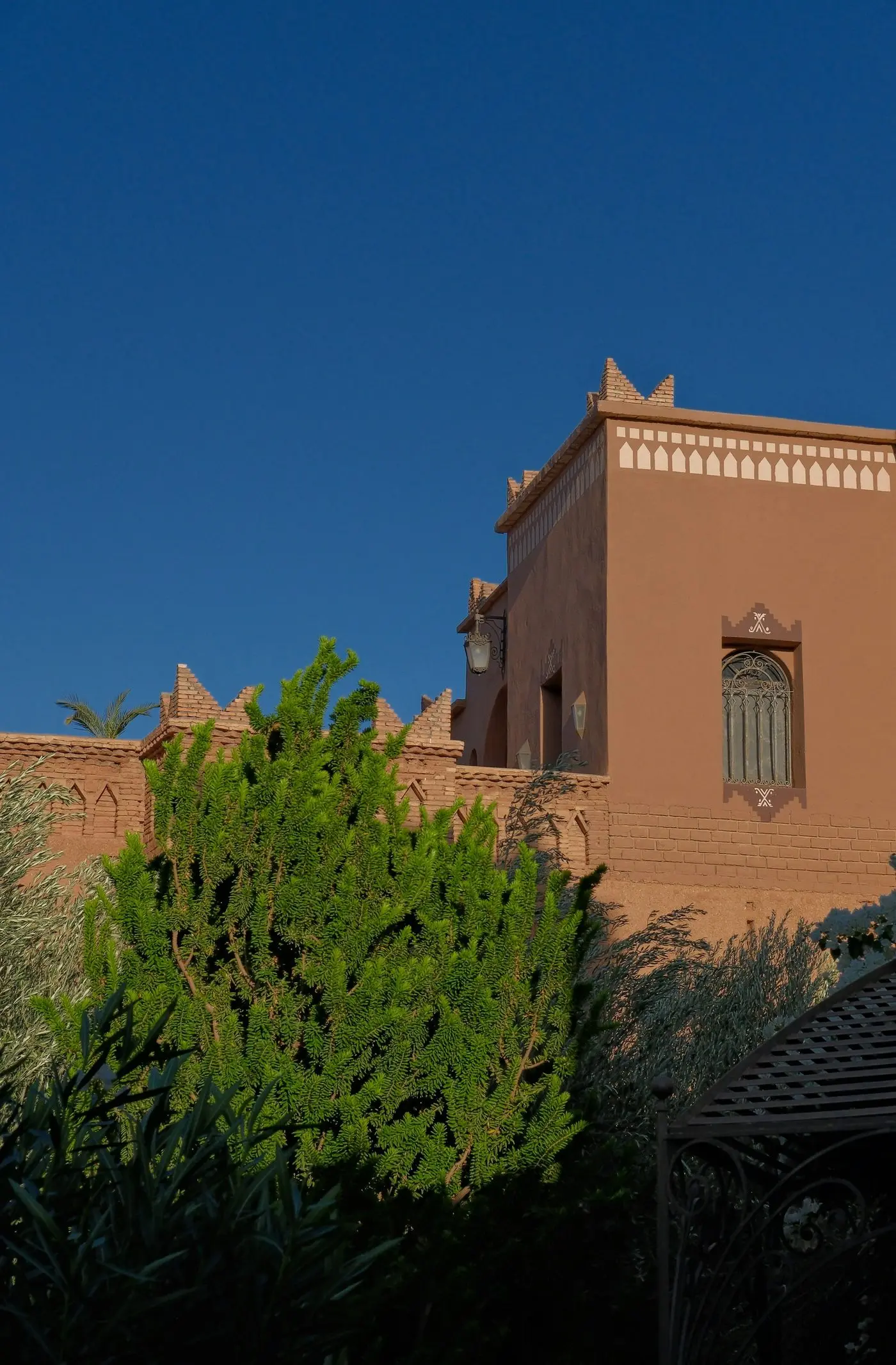 Bâtiment marocain traditionnel en terre ocre sous un ciel bleu profond